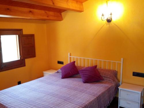 a bedroom with a bed with purple pillows and a window at Ca L'Estrada in Sant Esteve de Palautordera