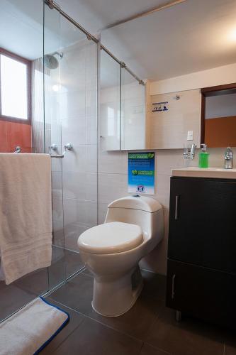 a bathroom with a toilet and a glass shower at Hotel Francés La Maison in Pasto