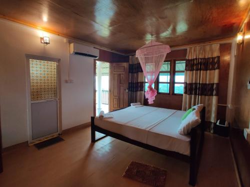 a bedroom with a large bed with a pink curtain at Sunntop Cabana in Trincomalee