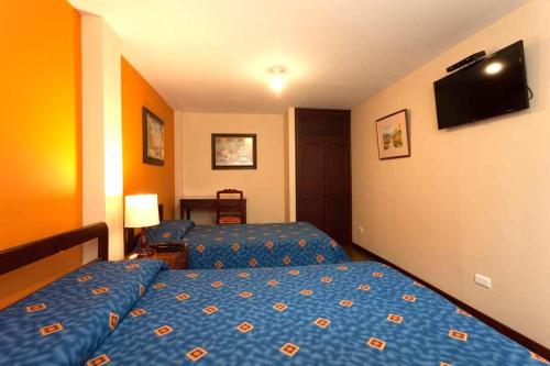 a bedroom with two beds and a flat screen tv at Hotel Francés La Maison in Pasto
