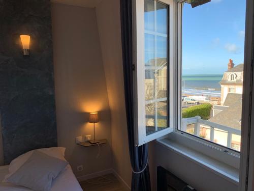 a bedroom with a window with a view of the ocean at Hôtel de la Plage in Houlgate