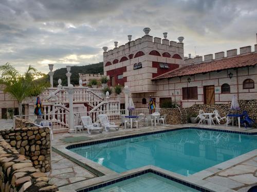 um hotel com piscina em frente a um edifício em Pousada al Castello di Giulietta e Romeo em Pirenópolis