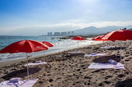 una playa con sombrillas rojas y sillas en la arena en Geotel Antofagasta en Antofagasta