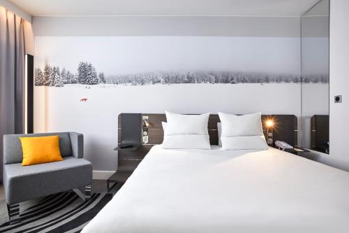a bedroom with a large bed and a chair at Novotel London Waterloo in London