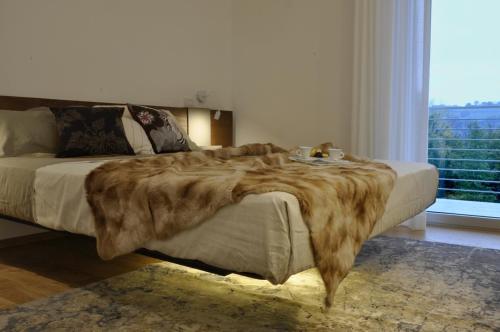 Una cama con una manta de piel falsa en un dormitorio en Chiaroscuro, en Belforte del Chienti