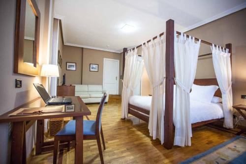 a bedroom with a bed and a desk with a laptop at Hotel Casa Camila in Oviedo