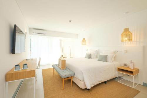 a white bedroom with a large bed and a desk at Malibu Foz Hotel - La Maison Younan in Figueira da Foz