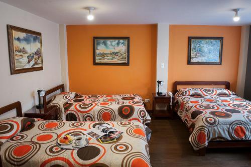 two beds in a room with orange walls at Hotel Francés La Maison in Pasto