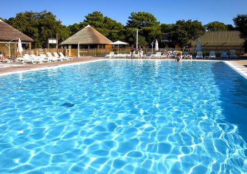 a large blue swimming pool with white chairs in it at Camping San Damiano in Biguglia