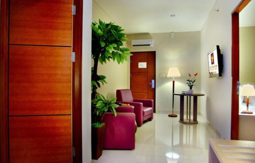 a living room with a pink couch and a plant at Kuta Central Park Hotel in Kuta