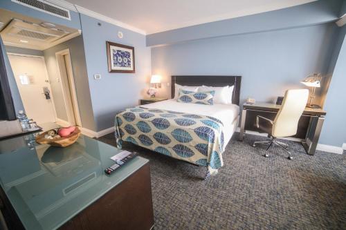 a hotel room with a bed and a desk and a television at The Jamaica Pegasus Hotel in Kingston