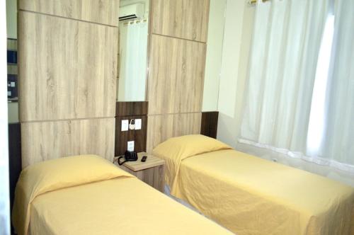a bedroom with two beds and a mirror at Santa Mônica Palace Hotel in Corumbá