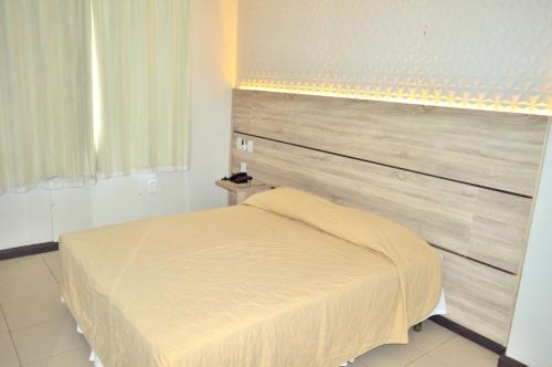 a bedroom with a bed with a large headboard at Santa Mônica Palace Hotel in Corumbá