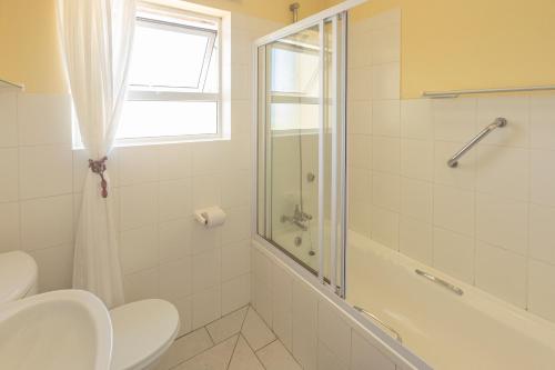 a bathroom with a toilet and a shower and a sink at Lyngenfjord House in Cape St Francis