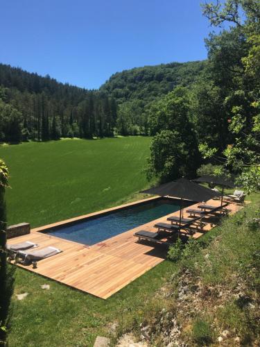 a pool with chairs and an umbrella in a field at Le Mas de Laval in Saint-Cirq-Lapopie