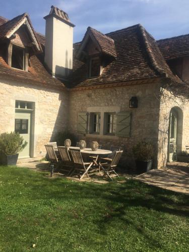 a house with a table and chairs in the yard at Le Mas de Laval in Saint-Cirq-Lapopie