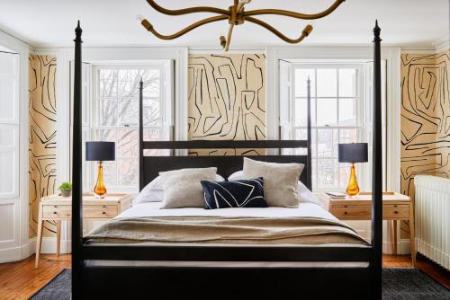 a bedroom with a black bed with two lamps at Blind Tiger Portland - Danforth Street Guest House in Portland