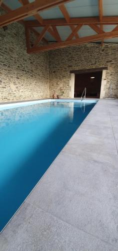 - une piscine dans un bâtiment en pierre avec une piscine bleue dans l'établissement Bed and Breakfast au Champ du Douits, à Saint-Agnan-le-Malherbe