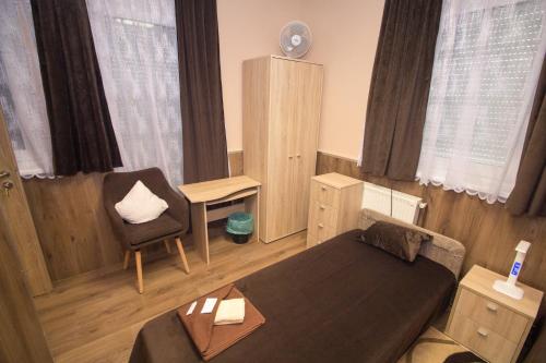 a small bedroom with a bed and a chair at M7 Galéria Panzió in Letenye
