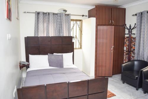a bedroom with a bed and a black chair at 3A's Guest House in Oko Sombo
