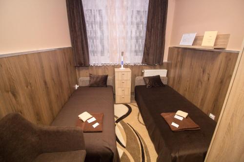 a room with two beds and a chair and a window at M7 Galéria Panzió in Letenye