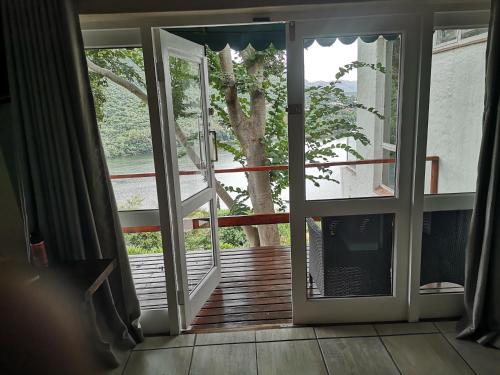 an open door to a deck with a tree outside at Letamong in Hartbeespoort