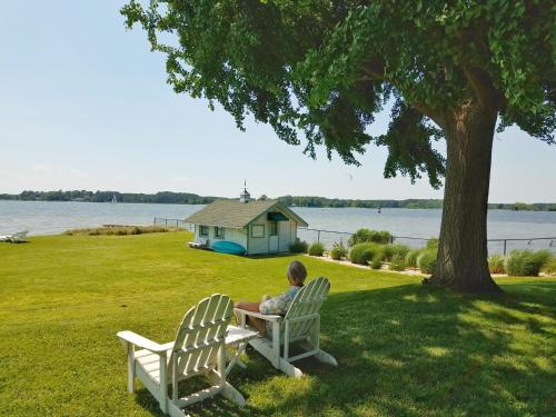 a man sitting in two chairs under a tree at Sandaway Suites & Beach in Oxford