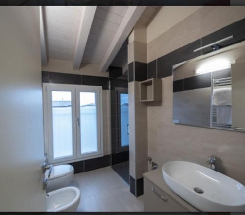 ein Badezimmer mit einem Waschbecken, einem WC und einem Spiegel in der Unterkunft Locanda la torre in Calvisano