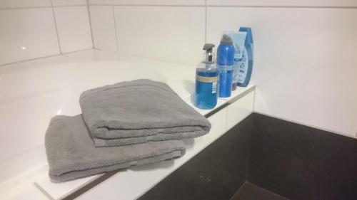 ein Badezimmer mit drei Handtüchern auf der Theke und einigen Flüssigkeiten in der Unterkunft K82 BNB & Hotel in Kirchentellinsfurt