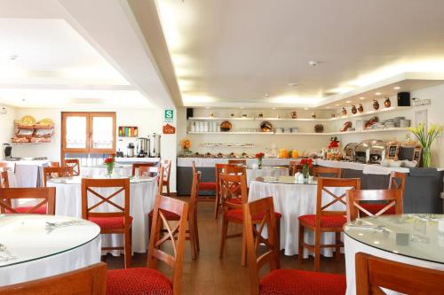 um restaurante com mesas e cadeiras e uma cozinha em San Agustin Plaza em Cusco