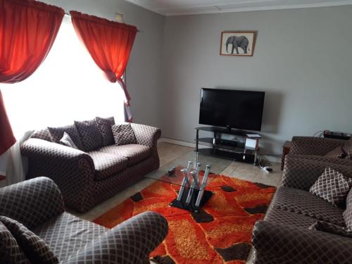 un soggiorno con 2 sedie e una TV a schermo piatto di Sheilas home away from home a Lusaka