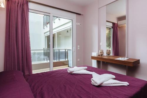 a bedroom with a purple bed with two white towels on it at Apanema Apartments in Vivari
