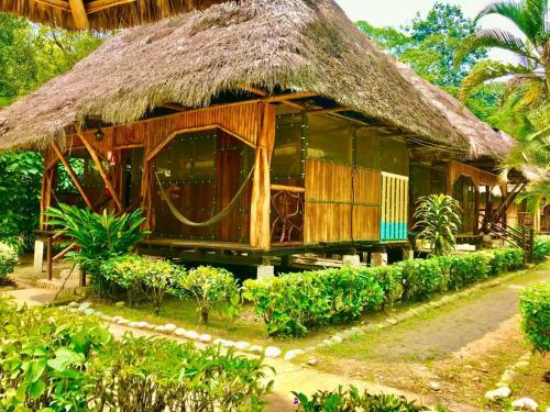 ein Haus mit einem Strohdach und einem Garten in der Unterkunft Isla Ecologica Mariana Miller in Puerto Misahuallí