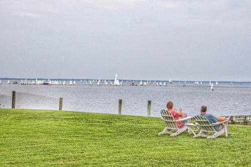 two people sitting in chairs on the grass near the water at Sandaway Suites & Beach in Oxford