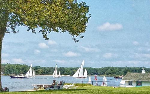 a group of sailboats on a lake with people sitting on the grass at Sandaway Suites & Beach in Oxford