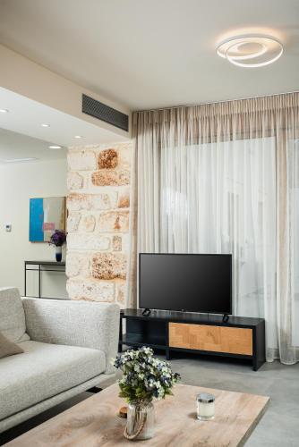a living room with a couch and a tv at Amaré Chania Luxury Residence in Stérnai