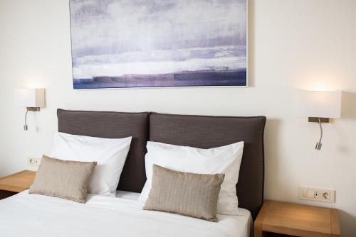 a bed with white pillows and a painting above it at Amaré Chania Luxury Residence in Stérnai