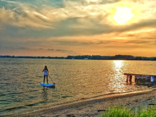 a woman standing on a paddle board in the water at Sandaway Suites & Beach in Oxford