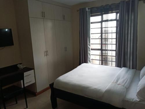 1 dormitorio con cama blanca y ventana en Nairobi west suite, en Nairobi