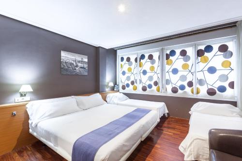 a bedroom with a large bed and two windows at Zumaia Hotela in Zumaia