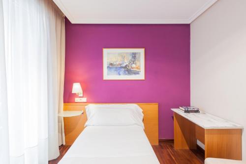 a bedroom with a purple wall and a bed at Zumaia Hotela in Zumaia