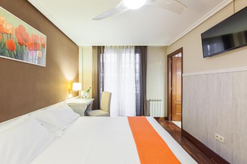 een hotelkamer met een groot bed en een televisie bij Zumaia Hotela in Zumaia