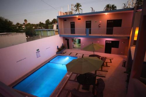 a house with a swimming pool with an umbrella at Hotel Del Mar in Barra de Navidad