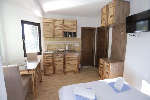 una cocina con armarios de madera, mesa y fregadero en Vila PARADIZO-ZLATAR, studio apartman 1 en Nova Varoš