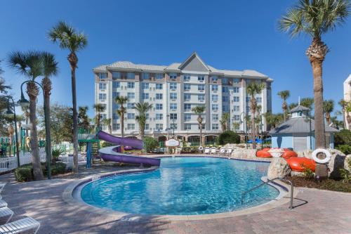 a resort with a slide in a pool with palm trees at Holiday Inn Express & Suites S Lake Buena Vista by IHG in Kissimmee
