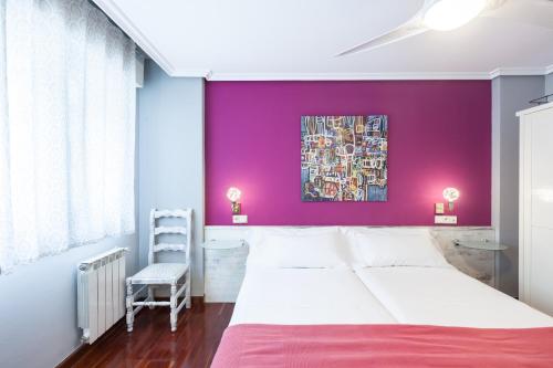 a bedroom with a purple wall with a bed and a chair at Zumaia Hotela in Zumaia