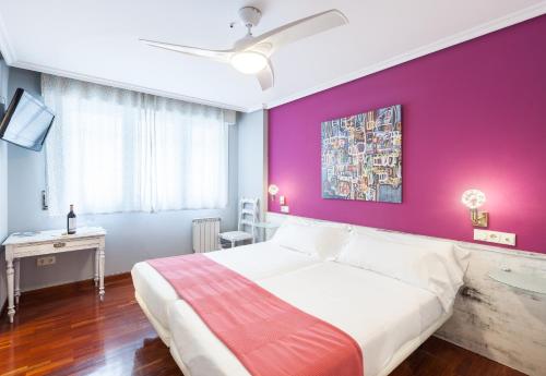 a bedroom with a purple wall and a bed at Zumaia Hotela in Zumaia