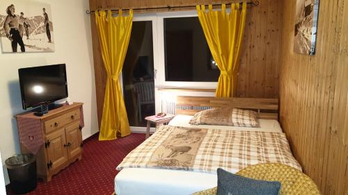 a bedroom with a bed and a window with yellow curtains at Hotel Mira in Sedrun