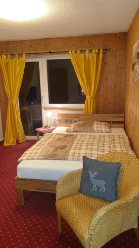 a bedroom with a bed and a chair with yellow curtains at Hotel Mira in Sedrun