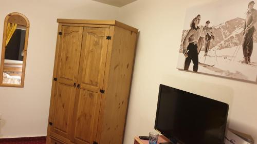a living room with a tv and a wooden cabinet at Hotel Mira in Sedrun